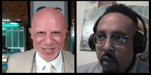 a man in a suit and tie is smiling next to another man with glasses and headphones