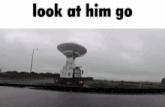 a black and white photo of a satellite dish with the words look at him go below it