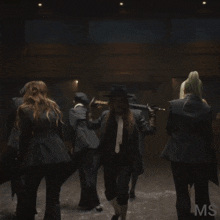 a group of people standing in a dark room with the word ms on the bottom right