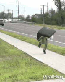 a person is running down a sidewalk with an umbrella on their back and the words viralhog on the bottom