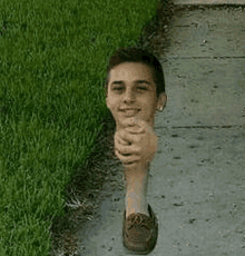 a man with his head sticking out of the grass is walking down the sidewalk .