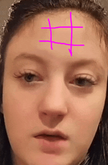 a close up of a girl 's face with a cross drawn on it .