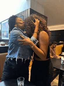 two women hugging in front of a sign that says ' ice cream '