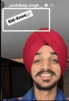 a man wearing a red turban and a blue shirt is smiling for the camera .