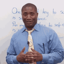 a man in a blue shirt and tie stands in front of a white board that says one key to sentence