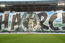 a large mural on the side of a stadium that says green mon on it