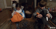 a boy and a girl are sitting at a table with candy on it and a netflix logo in the corner