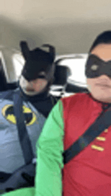 two people dressed as batman and robin are sitting in a car .