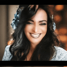 a woman with a flower in her hair is smiling and looking at the camera