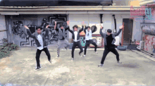 a group of young men are dancing in front of a wall with graffiti on it and a sign that says ' music park '