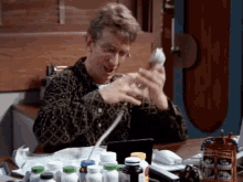 a man sits at a desk surrounded by bottles of medicine and a box that says ' dental ' on it