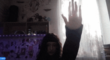 a person 's hand is visible in front of a window with a purple light behind them that says march