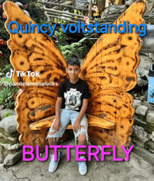 a boy is sitting on a bench with butterfly wings