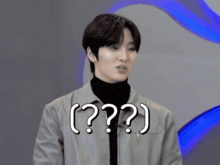 a man with a turtleneck and a jacket has a question mark on his chest