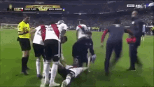 a soccer player is laying on the ground while a referee looks on during a game between river plate and boca juniors