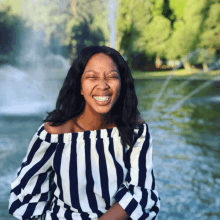 a woman wearing a black and white striped off the shoulder top is smiling