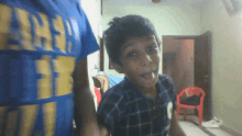 a boy wearing a blue shirt with the word area on it looks at the camera