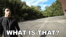 a man in a black shirt is standing in a parking lot with the words what is that above him