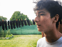 a young man standing in front of a clothes line with clothes hanging on it