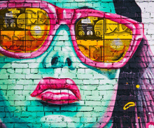 a brick wall has a painting of a woman 's face with sunglasses and a sign that says walking