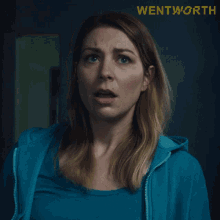 a woman in a blue hoodie is looking up with the word wentworth in yellow