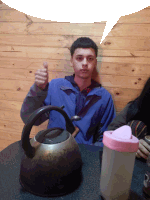 a man in a blue jacket giving a thumbs up next to a tea kettle