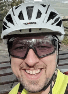 a man wearing a white helmet and sunglasses is smiling