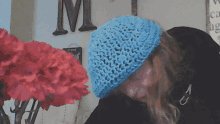 a woman wearing a blue crocheted hat is sitting in front of a large letter m