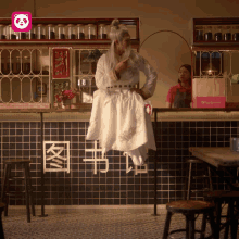 a man in a white dress is sitting on a counter in a restaurant with chinese writing on the wall