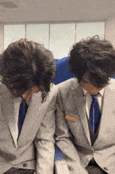 two men in suits and ties are sitting next to each other with their faces covered