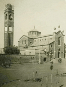 a black and white photo of a church with a clock tower in front of it