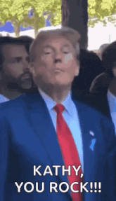 a man in a suit and tie is standing in front of a crowd and saying `` kathy , you rock ! ''