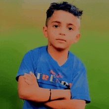 a young boy with his arms crossed wears a blue shirt that says trend