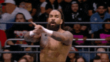a wrestler with a beard and bandages on his hands is pointing
