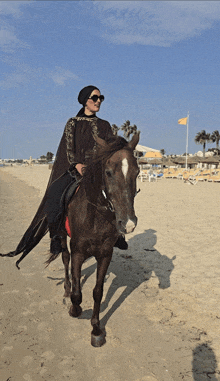 a woman in a hijab rides a horse on the beach