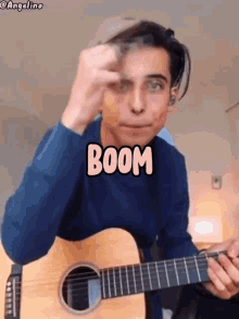 a young man is playing a guitar with the word boom written on it