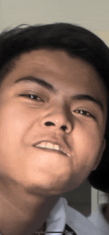 a close up of a young man 's face with a white shirt on