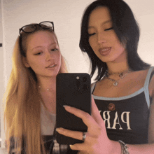 a woman taking a selfie with another woman wearing a tank top that says aa9