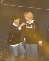 two men are standing next to each other on a stage and one of them is holding a microphone .