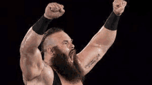 a bearded wrestler with his arms in the air .