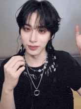 a young man wearing a black shirt and a necklace with a circle on it