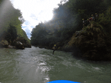 a group of people wearing yellow helmets are standing on a rock overlooking a river