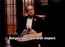 a man in a tuxedo is sitting at a desk and says but you don t ask with respect