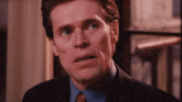 a close up of a man 's face with a blue shirt and a red tie