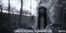 a black and white photo of a girl riding a bike with the words " time is flying so hurry up "