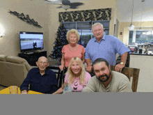 a group of people posing in front of a christmas tree