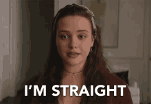 a woman is standing in a room with the words `` i 'm straight '' written on the screen .