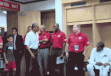 a group of men in red shirts are standing in a locker room with a sign above them that says ' locker room '