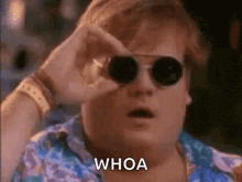 a man wearing sunglasses is looking through a pair of binoculars and says whoa .