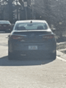 a car is parked on the side of the road with trees in the background